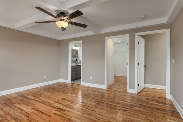 unfurnished bedroom with a walk in closet, ensuite bathroom, ceiling fan, light hardwood / wood-style floors, and a closet