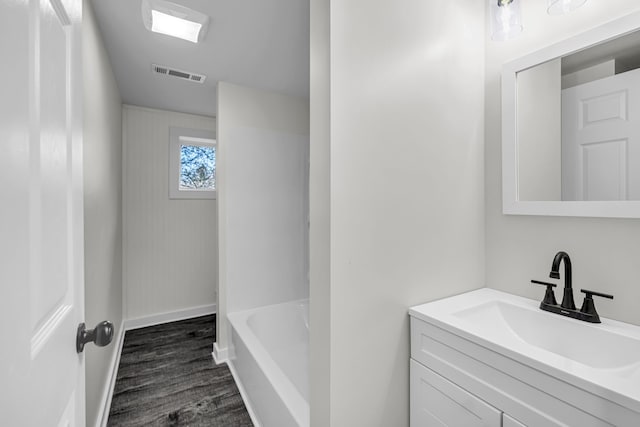 bathroom with hardwood / wood-style flooring, a tub to relax in, and vanity