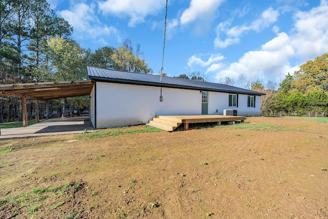 back of property with central AC unit, a wooden deck, and a carport