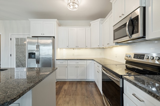 kitchen featuring appliances with stainless steel finishes, white cabinetry, dark stone countertops, and dark hardwood / wood-style floors