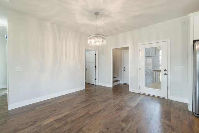 spare room featuring an inviting chandelier and dark hardwood / wood-style flooring