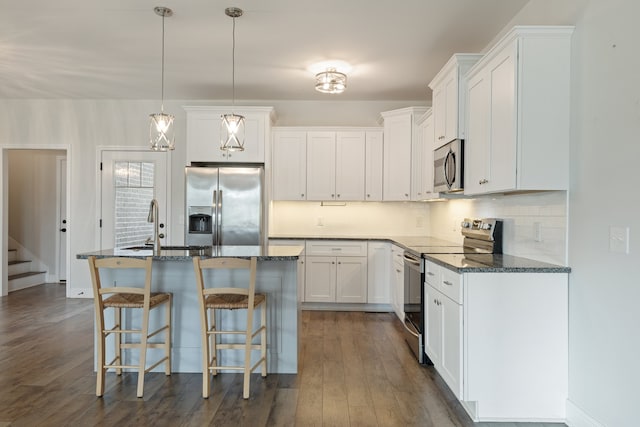 kitchen with white cabinetry, stainless steel appliances, an island with sink, and dark hardwood / wood-style floors