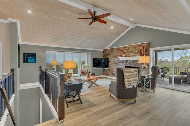 living room with lofted ceiling with beams, ornamental molding, a brick fireplace, and light wood-type flooring