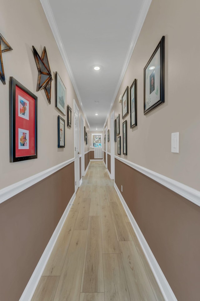 corridor featuring ornamental molding and light hardwood / wood-style flooring