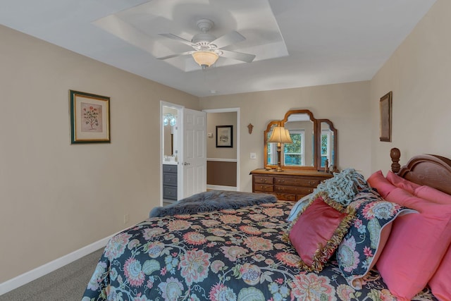 bedroom with a raised ceiling, carpet flooring, ceiling fan, and ensuite bath