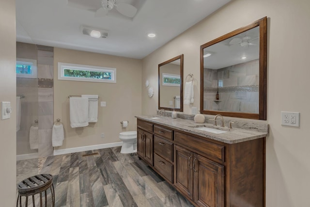 bathroom featuring vanity, tiled shower, ceiling fan, and toilet