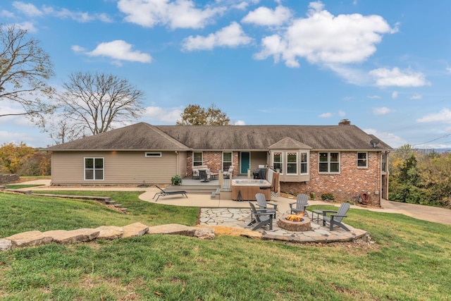 rear view of property with a yard, a fire pit, a hot tub, and a patio