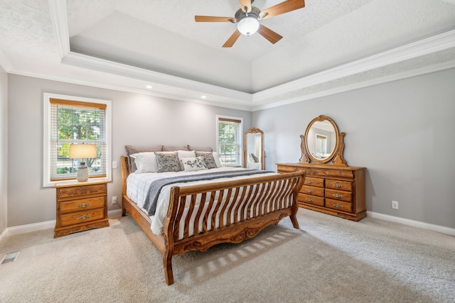 bedroom featuring ceiling fan, multiple windows, a raised ceiling, and light colored carpet