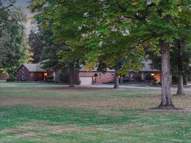 view of property hidden behind natural elements featuring a garage and a front yard