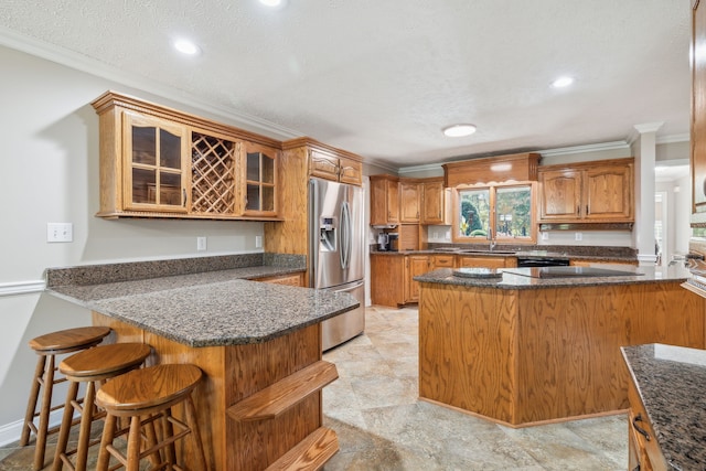 kitchen with kitchen peninsula, a textured ceiling, and stainless steel fridge