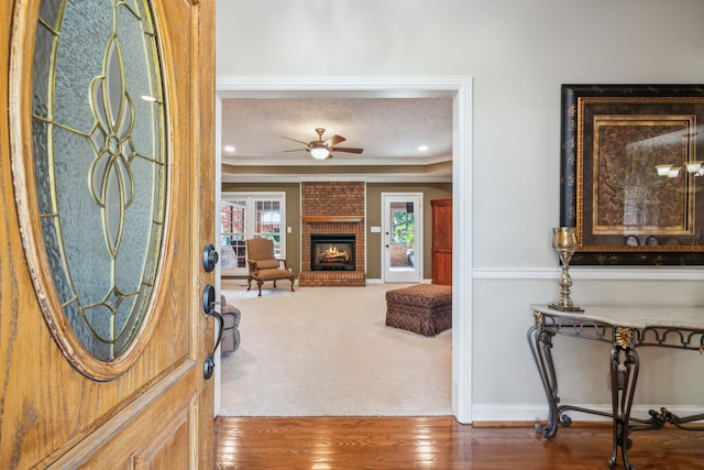 entryway featuring ornamental molding, a fireplace, and hardwood / wood-style flooring