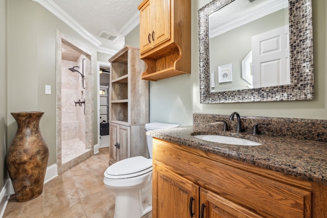 bathroom with a textured ceiling, a tile shower, vanity, crown molding, and toilet