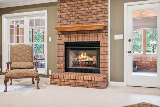 sitting room with a brick fireplace, carpet flooring, and crown molding