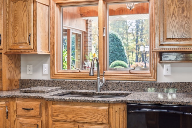 kitchen with dark stone countertops, sink, and dishwasher