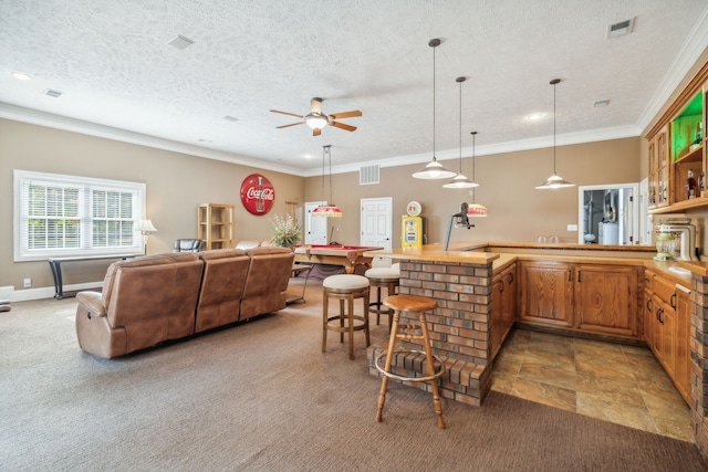 kitchen featuring pendant lighting, ornamental molding, a textured ceiling, and a breakfast bar area