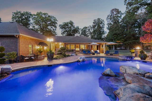 pool at dusk featuring a patio