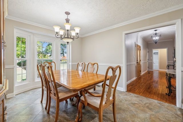 dining space featuring hardwood / wood-style floors, a textured ceiling, a notable chandelier, and ornamental molding