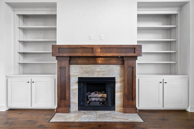 details featuring a tiled fireplace, hardwood / wood-style flooring, and built in features