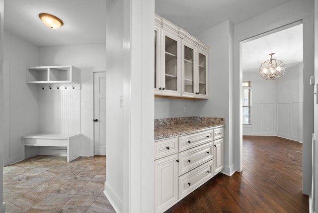 kitchen with an inviting chandelier, light stone countertops, white cabinetry, and light wood-type flooring