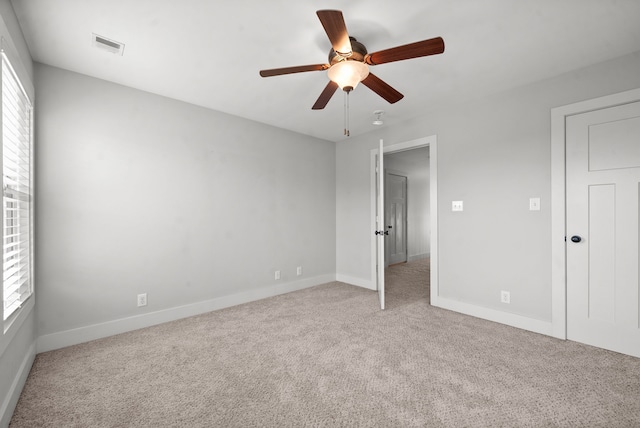 unfurnished bedroom with multiple windows, light colored carpet, and ceiling fan