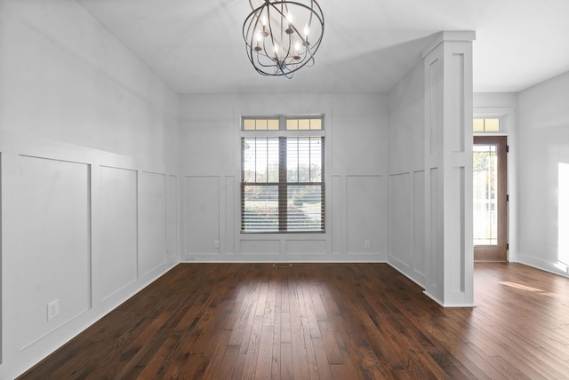 empty room with dark wood-type flooring, a wealth of natural light, and an inviting chandelier