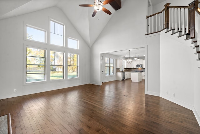 unfurnished living room with a wealth of natural light, dark wood-type flooring, and high vaulted ceiling