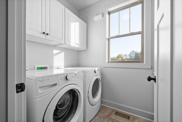 laundry room featuring a wealth of natural light, washing machine and clothes dryer, and cabinets