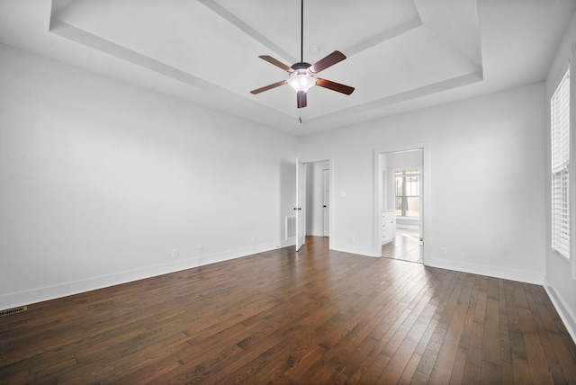 unfurnished room with a tray ceiling, dark wood-type flooring, and ceiling fan