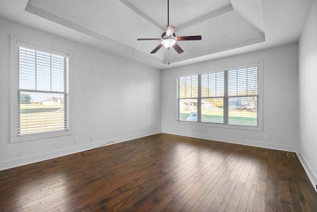 unfurnished room featuring a tray ceiling, dark wood-type flooring, and ceiling fan