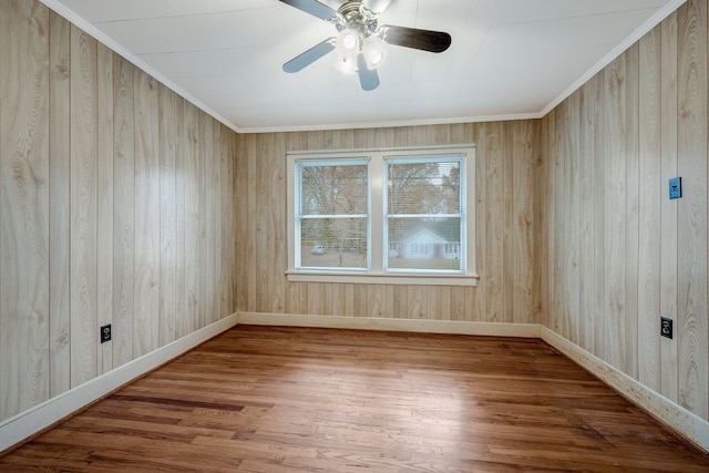 empty room featuring hardwood / wood-style flooring, wood walls, and ornamental molding