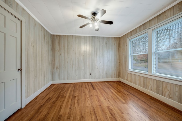 spare room with hardwood / wood-style flooring, ceiling fan, wood walls, and ornamental molding