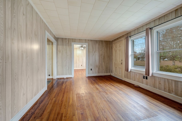 spare room with wood walls, ceiling fan, and wood-type flooring