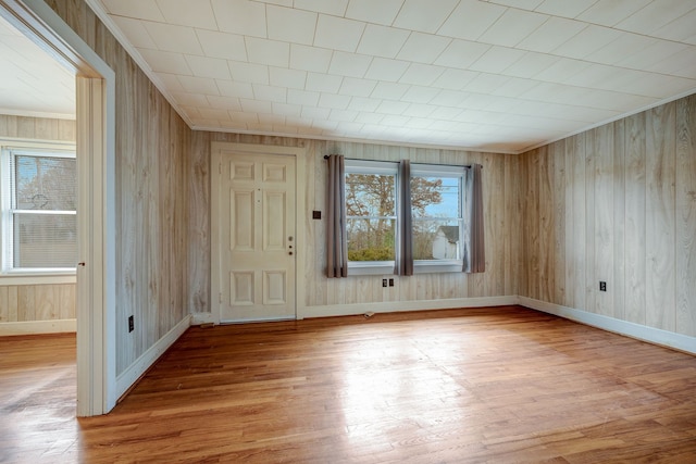 foyer entrance with light hardwood / wood-style flooring and wood walls