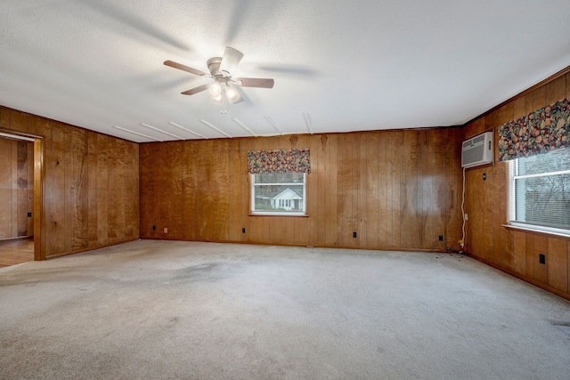 unfurnished room featuring wooden walls, ceiling fan, light colored carpet, and a wall mounted air conditioner