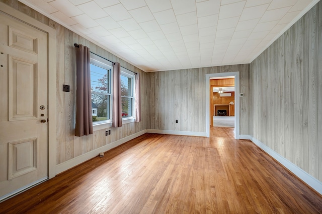 unfurnished room featuring light wood-type flooring and wooden walls