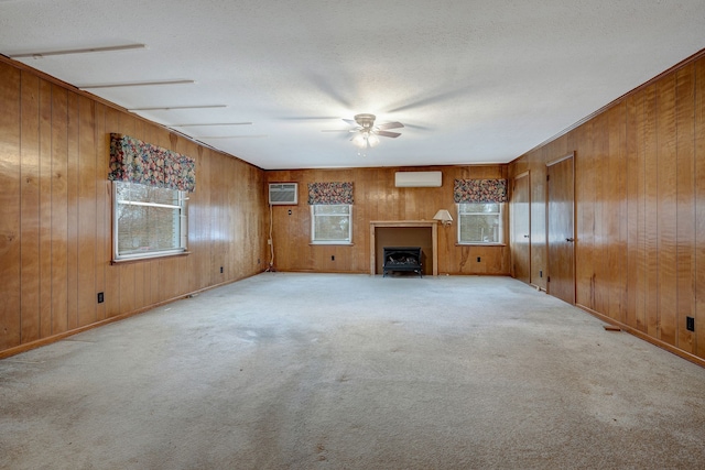 unfurnished living room featuring a wall mounted AC, wood walls, and light carpet