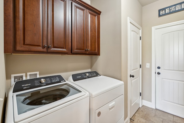 washroom with washer and dryer, light tile patterned flooring, and cabinets