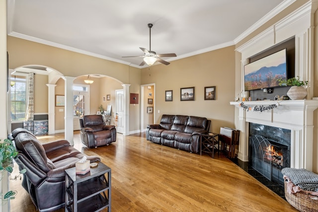 living room with ornate columns, hardwood / wood-style flooring, a premium fireplace, and ornamental molding