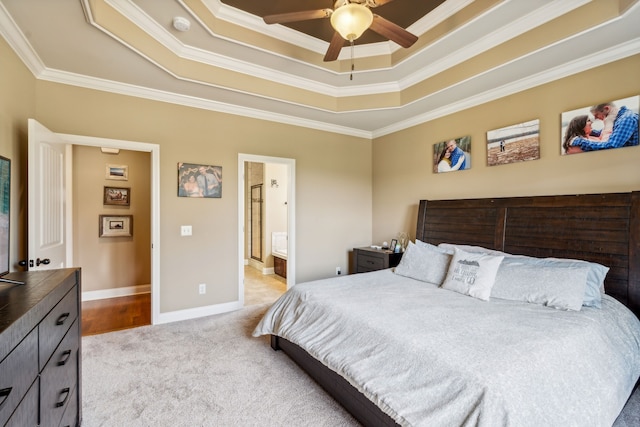 bedroom featuring light carpet, a raised ceiling, ceiling fan, ensuite bathroom, and crown molding