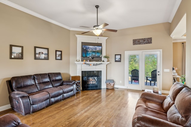 living room featuring light hardwood / wood-style flooring, a high end fireplace, crown molding, and ceiling fan