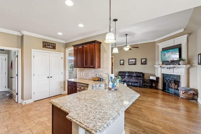 kitchen with kitchen peninsula, a premium fireplace, sink, light hardwood / wood-style floors, and ceiling fan