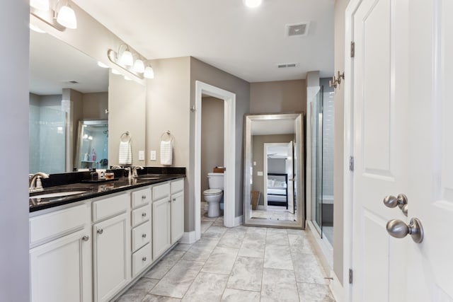 bathroom featuring vanity, a shower with shower door, and toilet