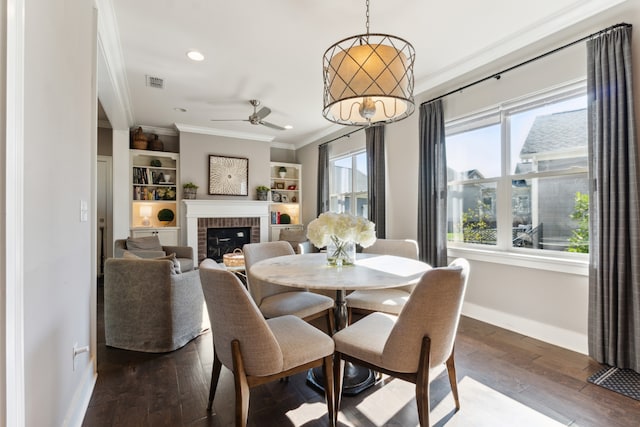 dining room featuring hardwood / wood-style flooring, crown molding, a brick fireplace, built in features, and ceiling fan