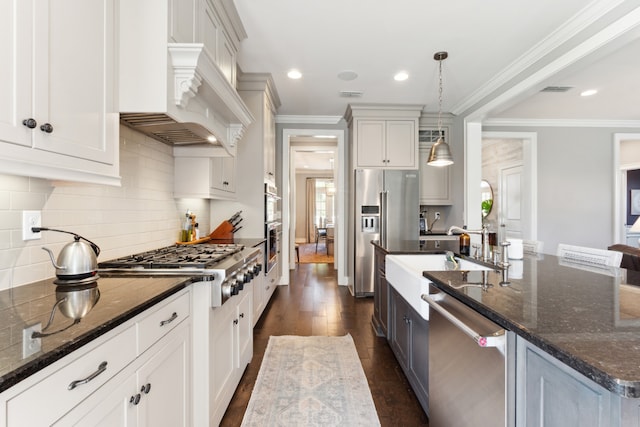 kitchen with dark hardwood / wood-style floors, stainless steel appliances, dark stone countertops, decorative light fixtures, and white cabinetry