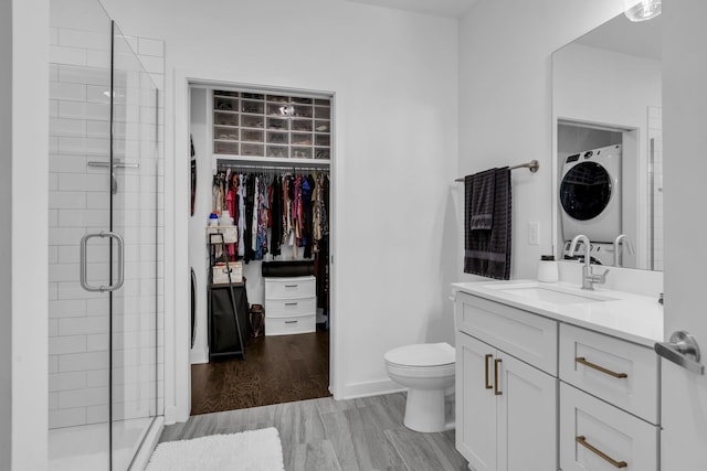 bathroom with vanity, walk in shower, stacked washer and clothes dryer, and hardwood / wood-style floors