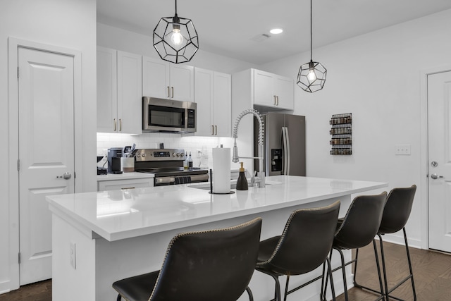 kitchen with pendant lighting, a kitchen island with sink, stainless steel appliances, and a breakfast bar