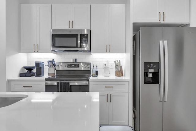 kitchen featuring white cabinetry, stainless steel appliances, and backsplash