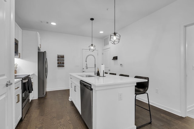 kitchen with appliances with stainless steel finishes, dark hardwood / wood-style flooring, white cabinets, a breakfast bar area, and a center island with sink