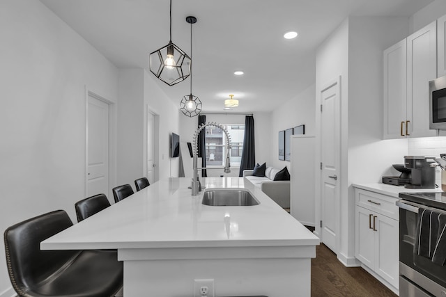 kitchen featuring sink, a kitchen island with sink, decorative light fixtures, and a breakfast bar