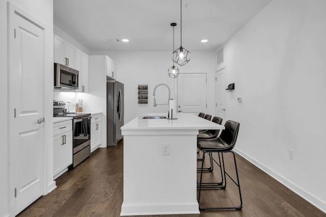 kitchen featuring a kitchen island with sink, stainless steel appliances, a kitchen bar, white cabinets, and dark hardwood / wood-style flooring